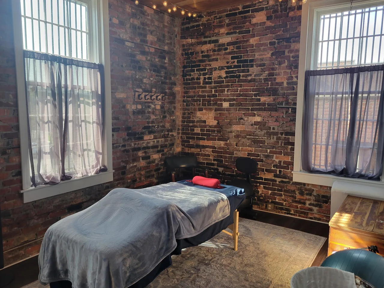 The warm, brick-walled therapeutic bodywork room at Transcendent Wellness in downtown New Bern