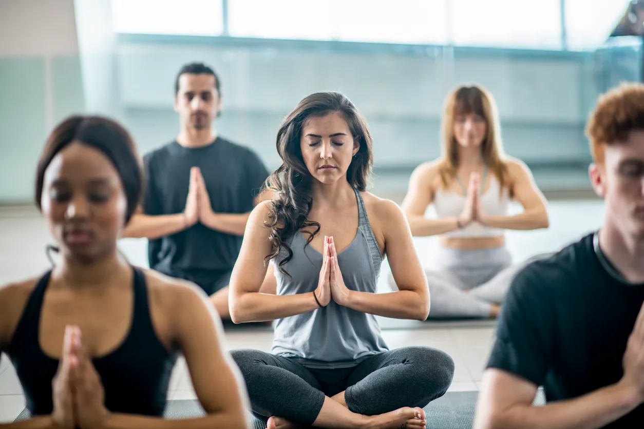 A group seated in quiet, guided meditation in a bright studio