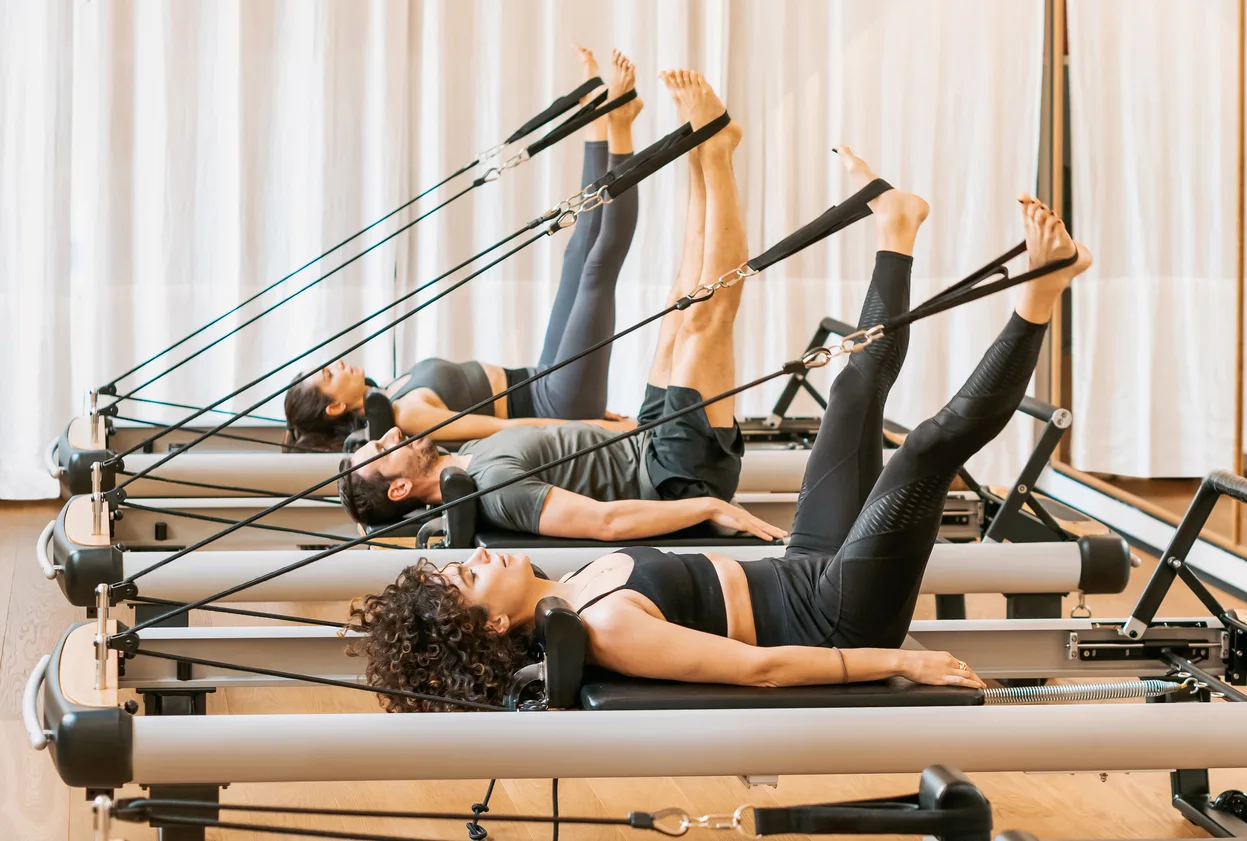 A Reformer Pilates class working on the reformers in a bright studio