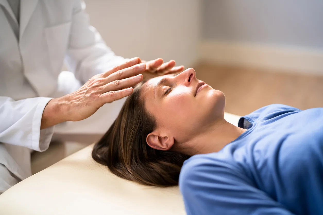 A practitioner holding their hands gently above a client's head during a Reiki session