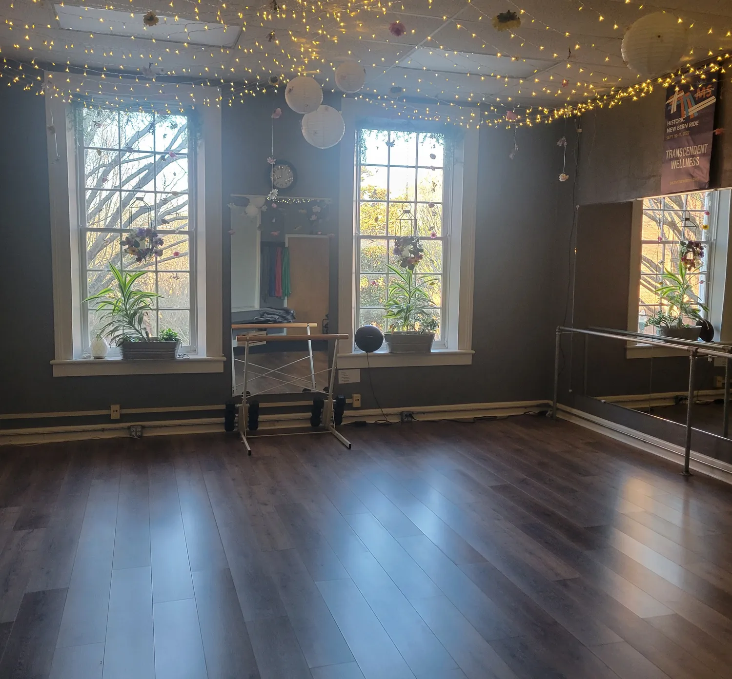 The warm, string-lit Transcendent Wellness studio in downtown New Bern, NC, with tall windows and wood floors